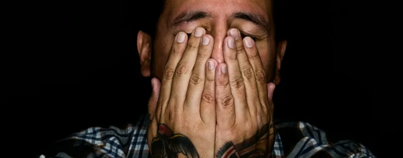 man wearing black, white, and gray plaid sport shirt covering his face